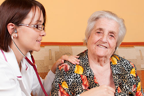 Doctor listens to heartbeat of her elderly patient