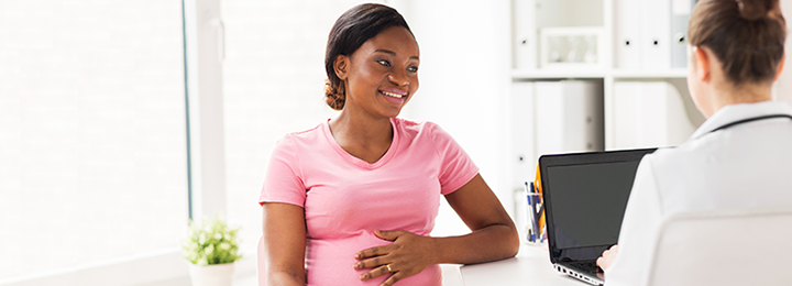 Pregnant mother talking with doctor holding stomach