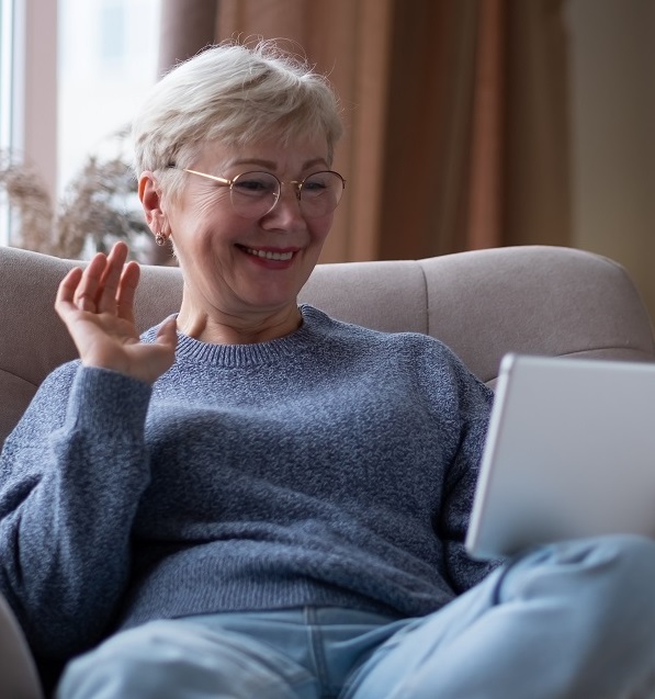 Woman waving using iPad for telemedicine visit.