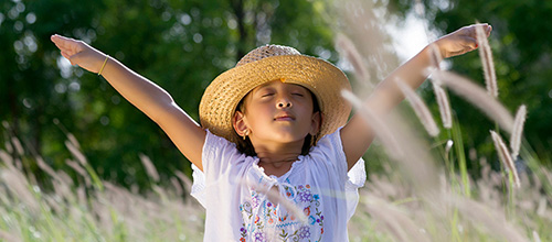 girl in a field taking a deep breath