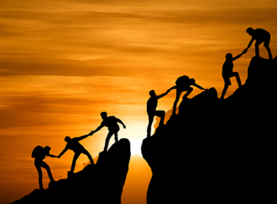 People helping each other climb up a mountain