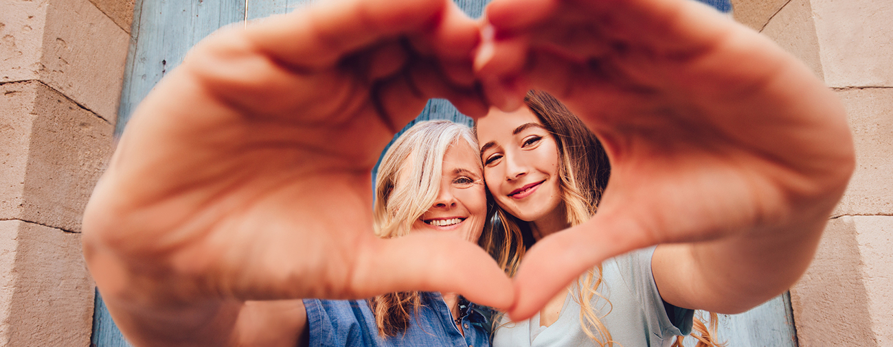 adult and teen making a heart shape with their hands with her hands