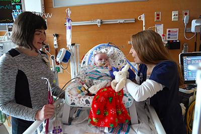 Baby in a crib with two providers