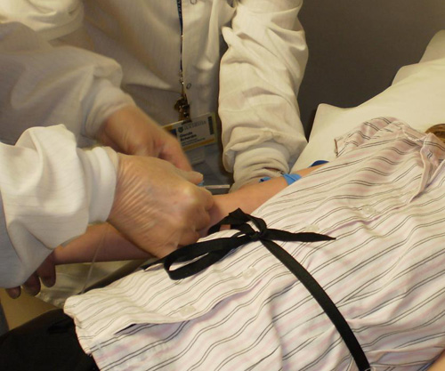 Phlebotomist quickly poking a patient with a butterfly needle