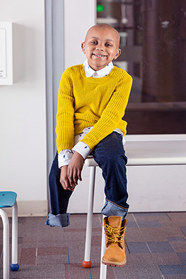 Myles Davis Smiling, sitting on a desk.