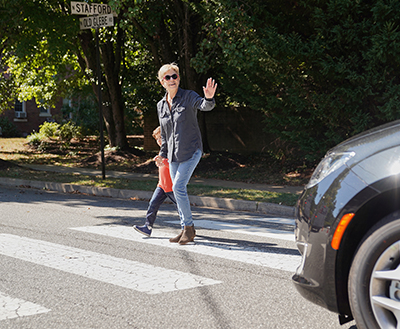 Young child crossing street with an adult