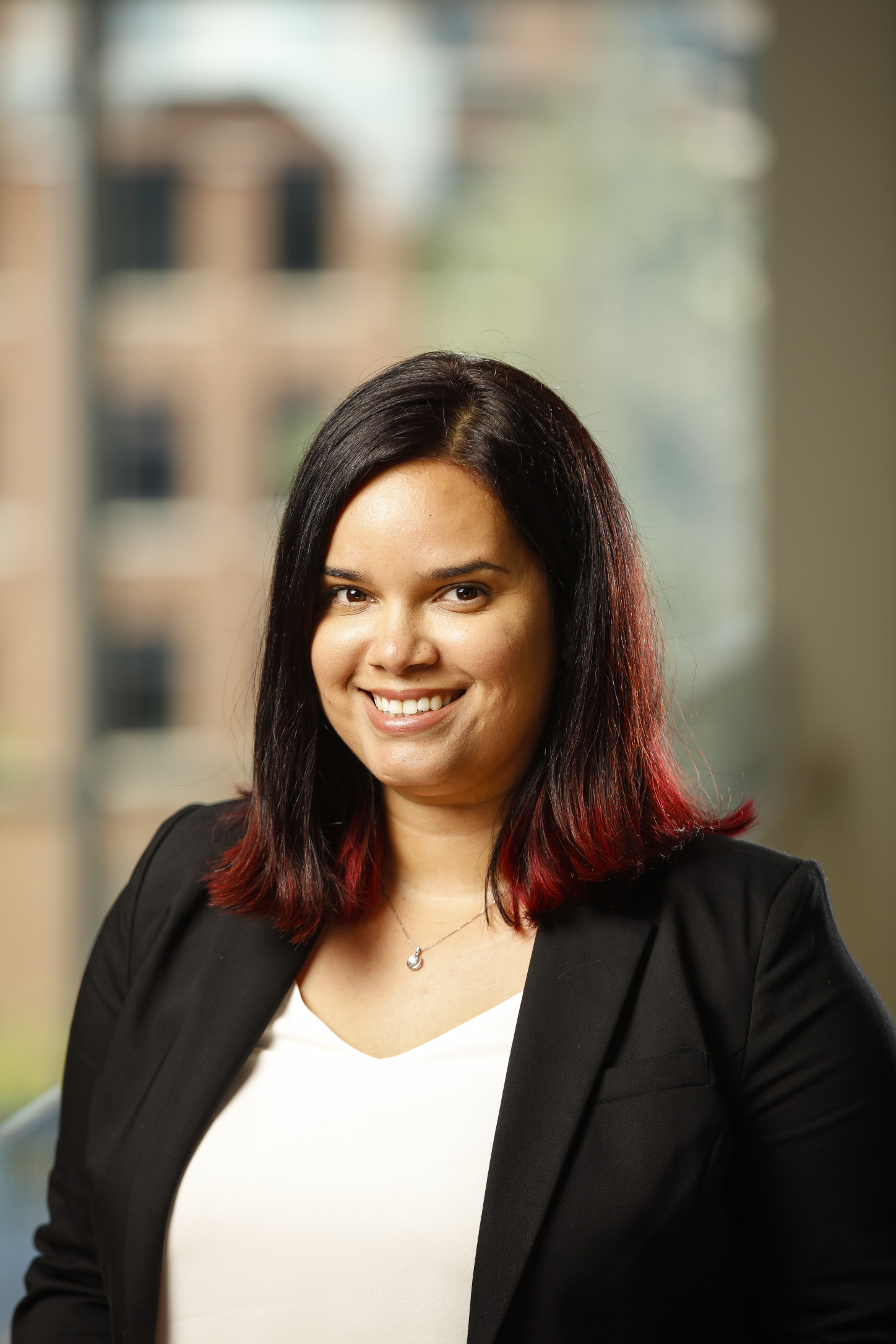 person standing with black blazer smiling at camera