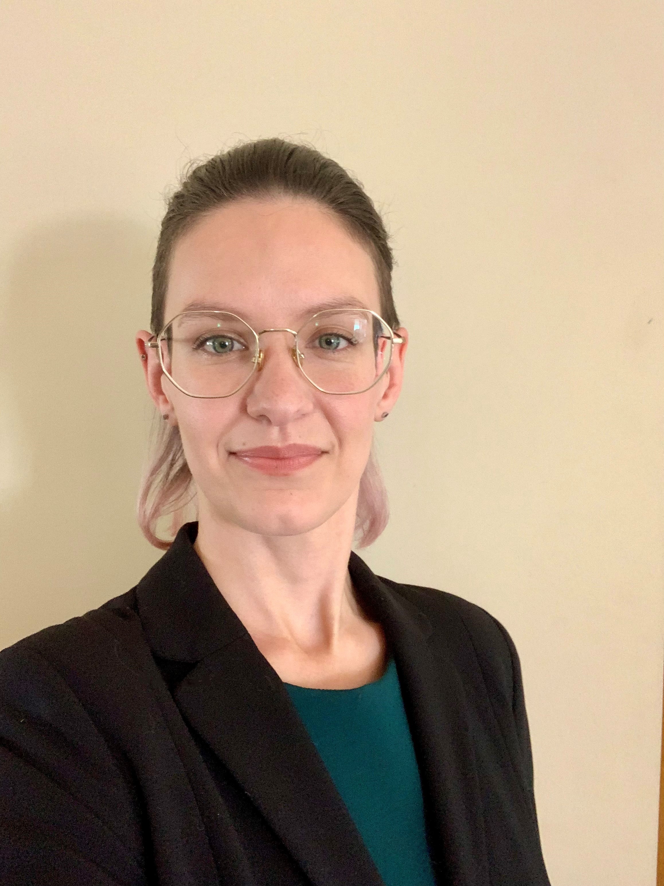 person with glasses and black blazer looking at camera