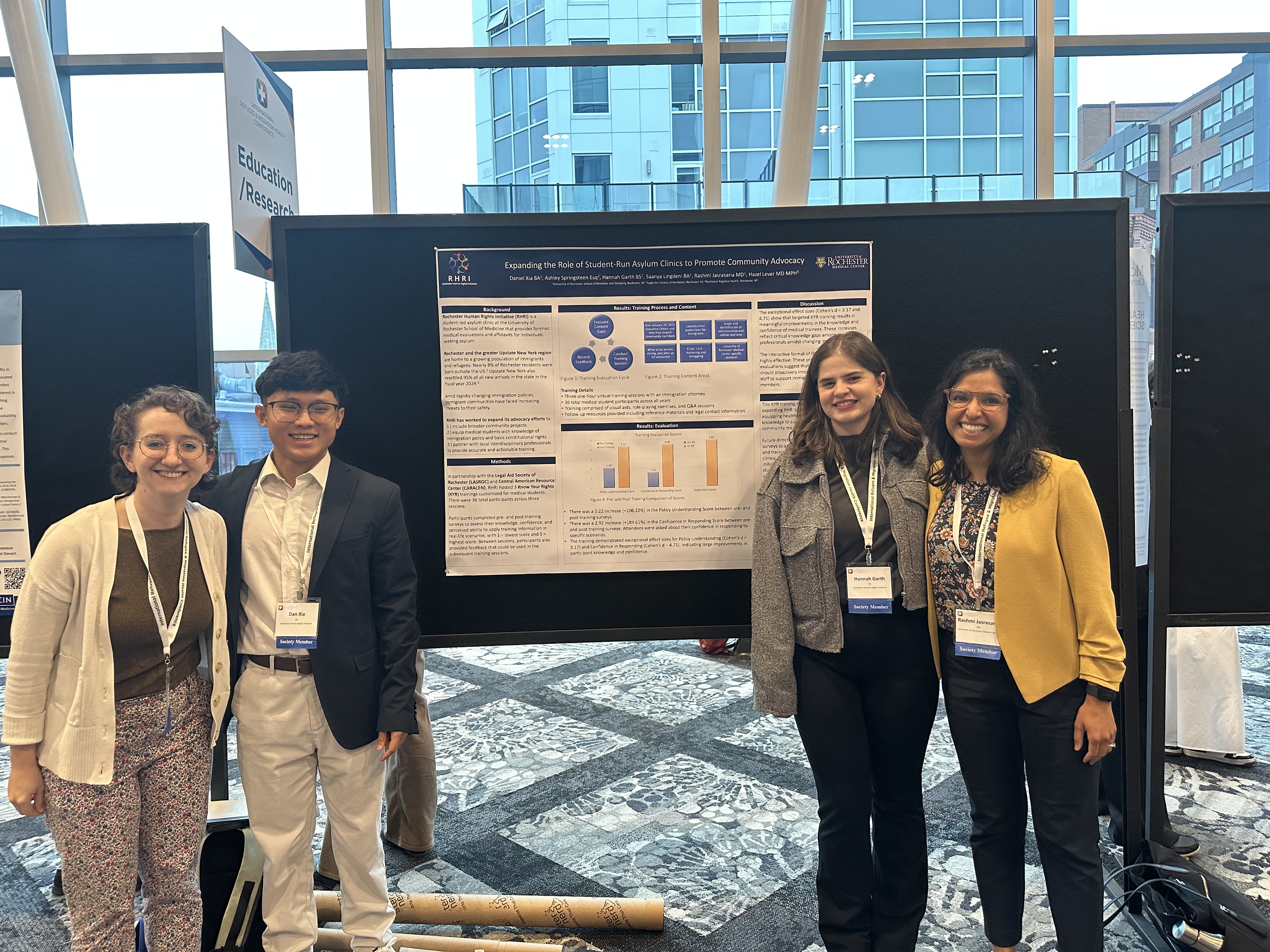 Group of four people at a conference standing in front of an academic research poster