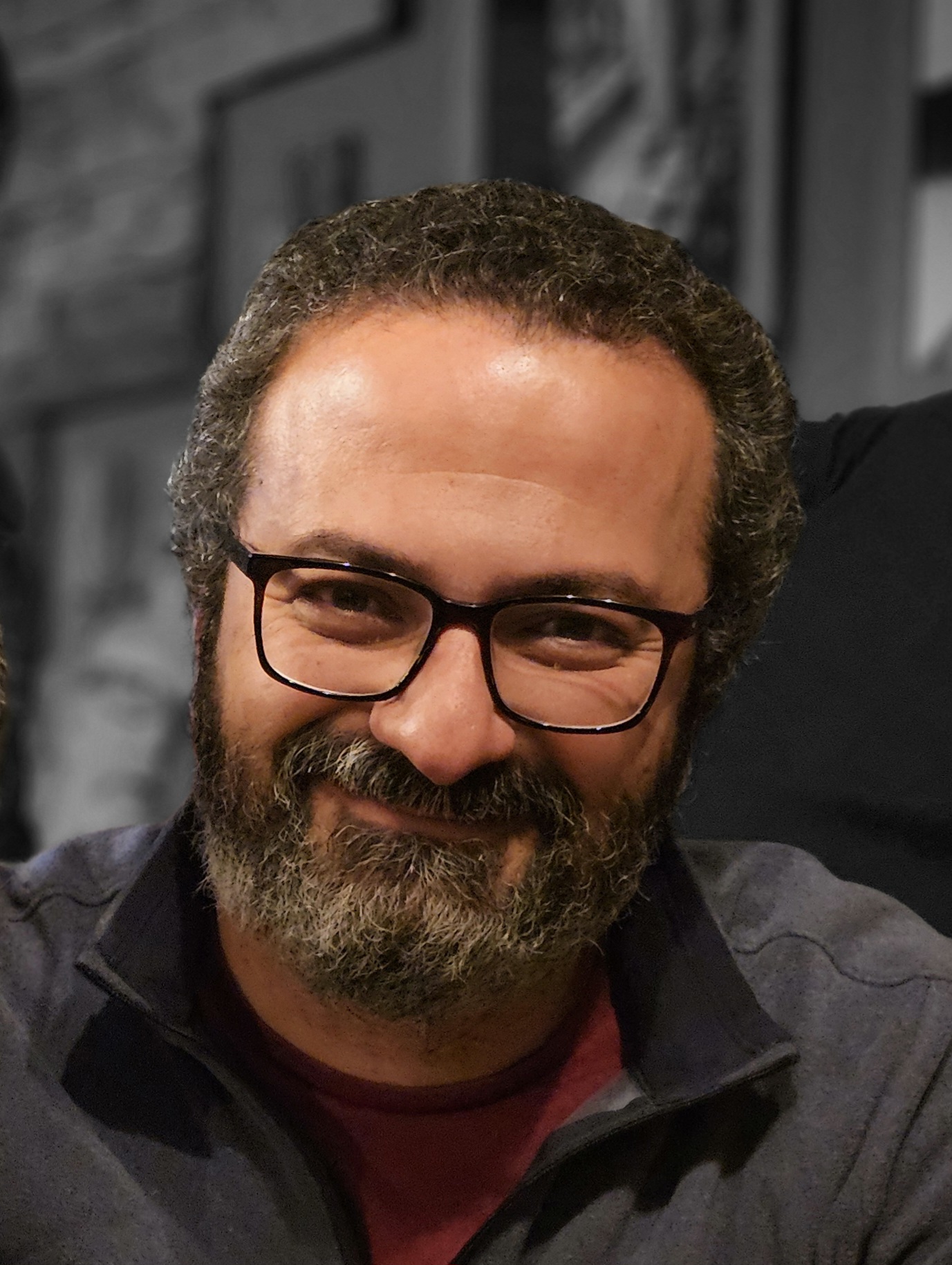 Person with glasses and facial hair smiling at camera