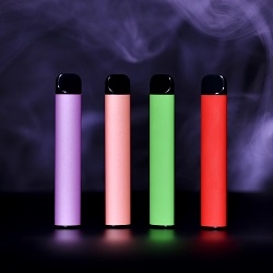 Purple, pink, green, and red vaping devices surrounded by purple smoke