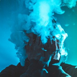 Man's face lost in a cloud of vape smoke.