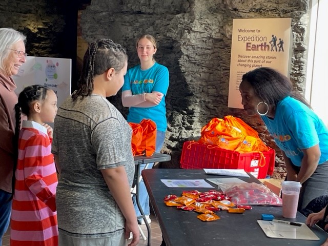 Kids talk with faculty member at table during event.