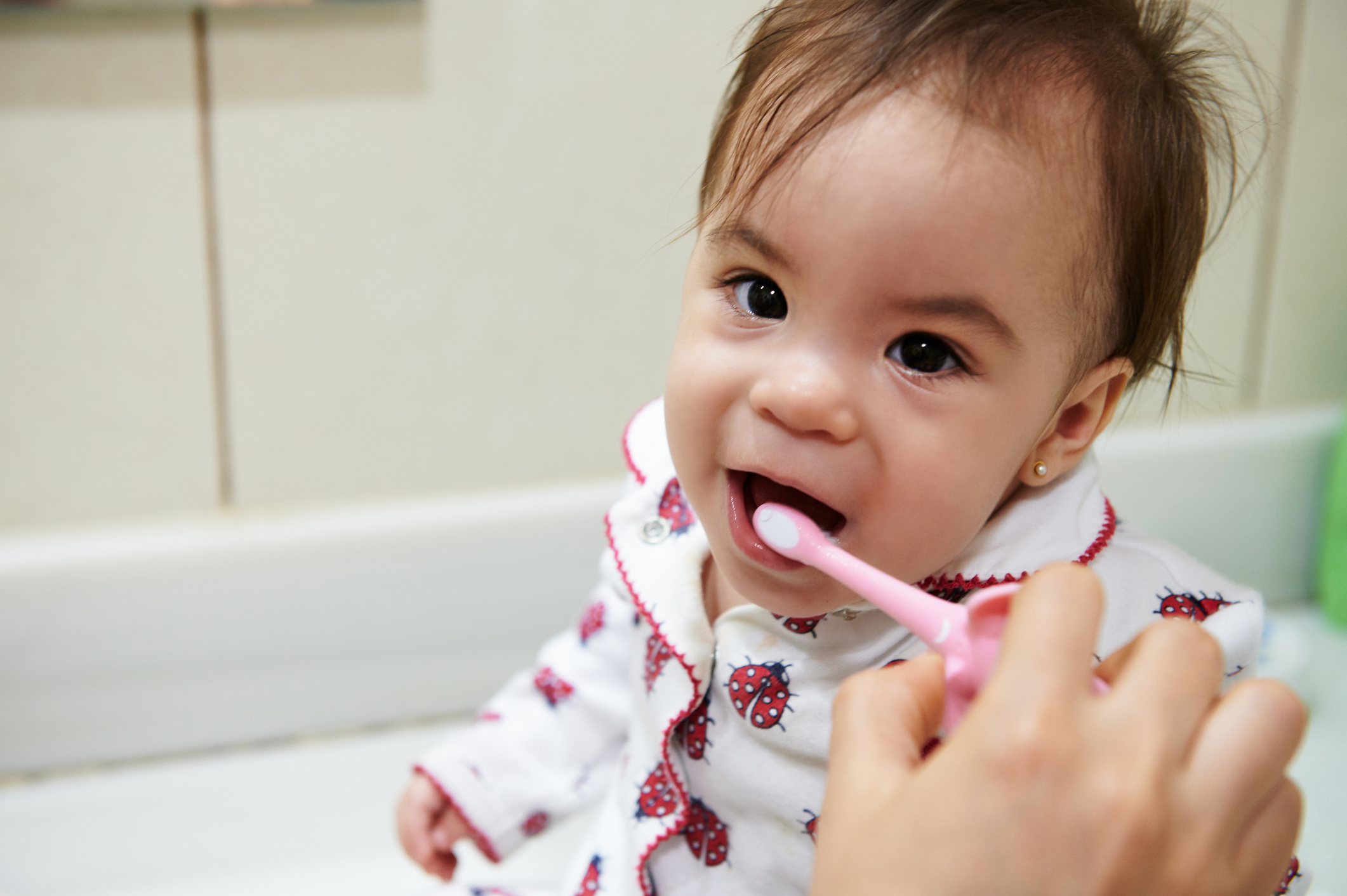 a parent brushes a baby's teeth
