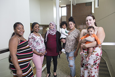 3 pregnant women stand next to 2 women holding babies