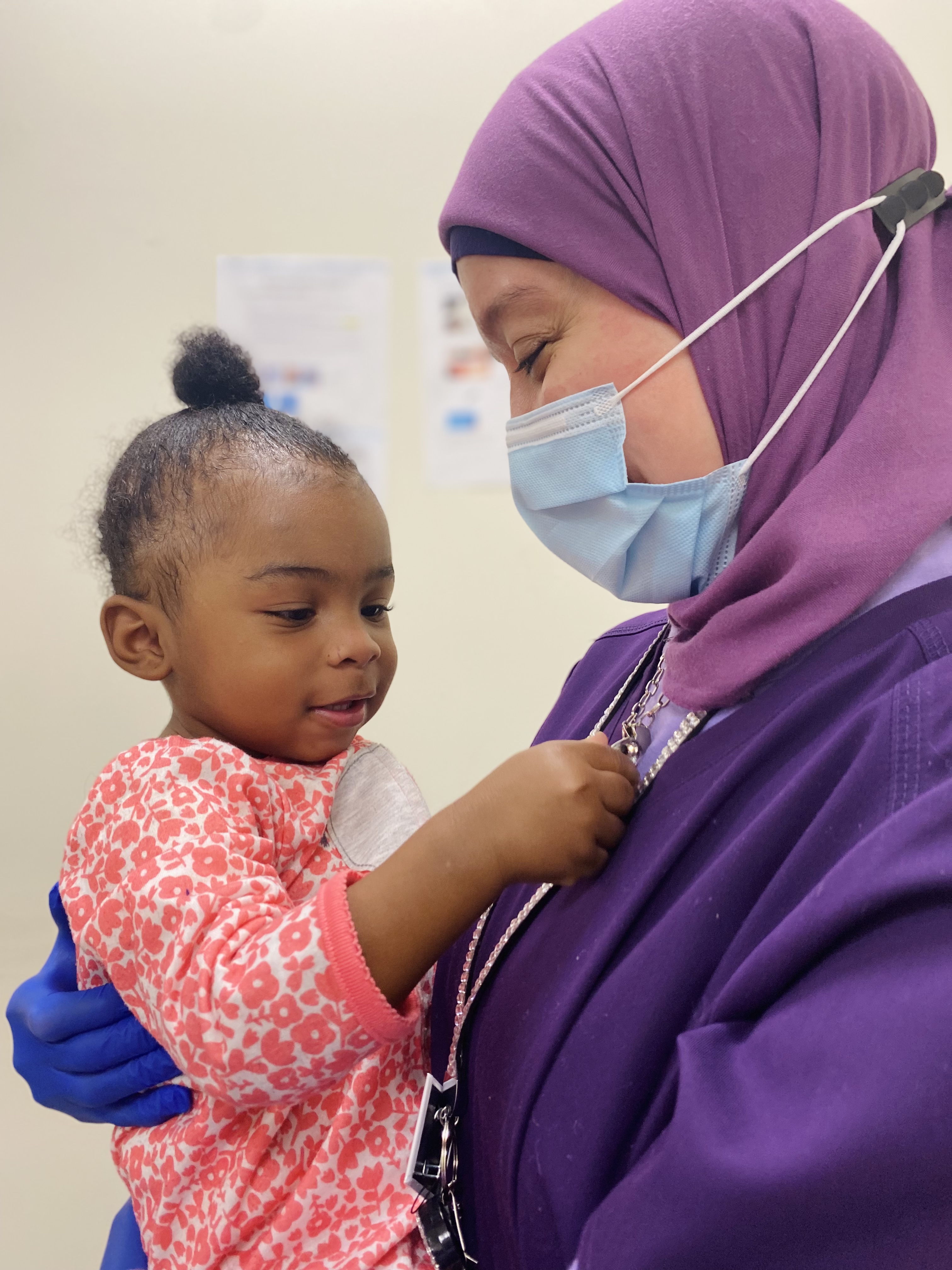 a woman wearing a mask holds a happy baby
