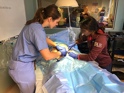 Residents practicing a surgical procedure on a dummy