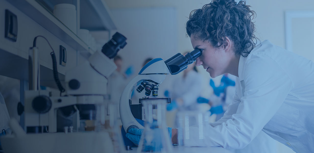 postdoc researcher in lab peering through microscope