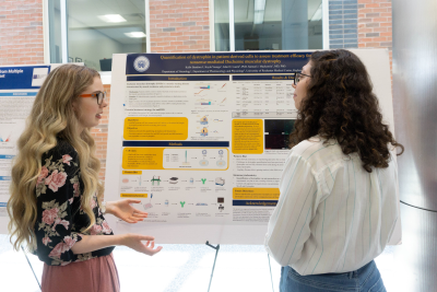 2024 MSTP Summer Scholar, Kelbi Banducci, presenting to a student at the Summer Scholars Poster Session.