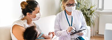 Woman holding child next to visiting nurse