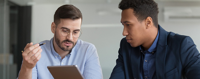 two men looking at a tablet