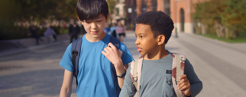 2 boys walking and talking outside their school