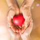 Two people's hands holding a heart