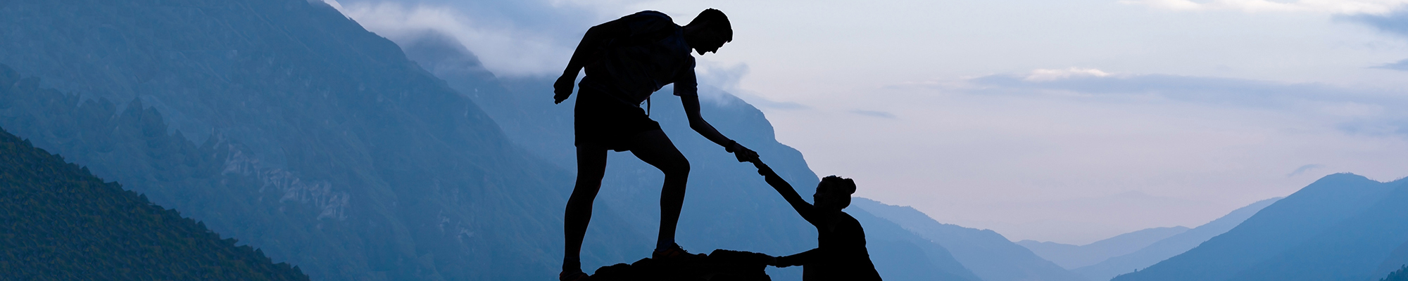 Man helping a woman climb a mountain