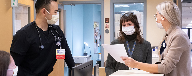 group of medical standing and talking around desk in medical unit