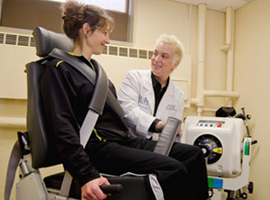 A woman using an exercise machine under supervision