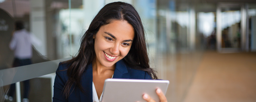 A woman looking at a computer tablet and smiling