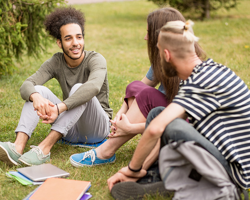 3 teens talking sitting on grass