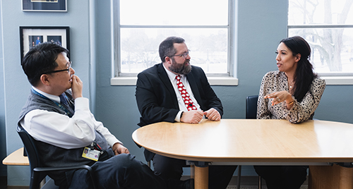 Ben Lee, Michael Scharf, Courtney Blackwood talking at a table