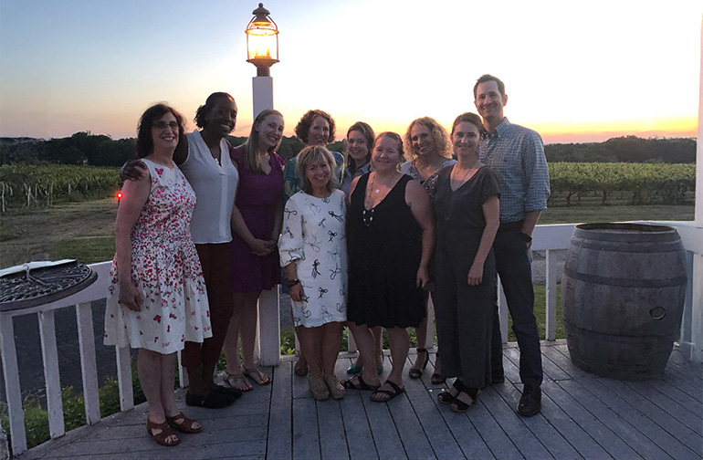 group of faculty standing in front of vineyard