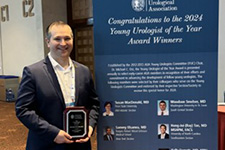 Scott Quarrier Holding a Plaque Next to a Congratulatory Banner